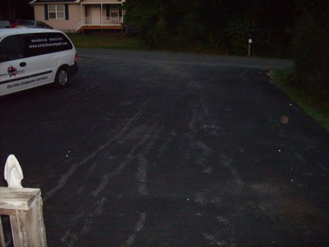 2004 Ford Crown Victoria - A white van with company branding is parked on an asphalt driveway in front of a house.