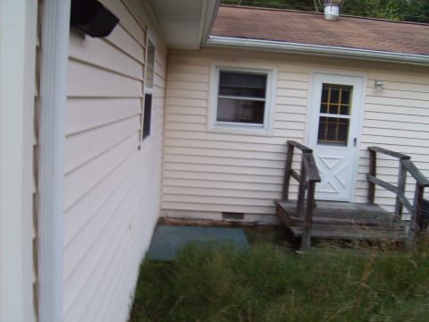 2004 Ford Crown Victoria - The side of a house with vinyl siding, a window, and a white door with a cross-patterned window.