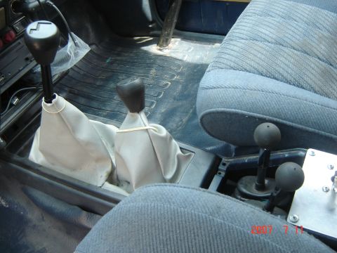 1993 Ford Bronco - Interior view of a vehicle's center console, showing multiple gear shifters and worn blue seats.
