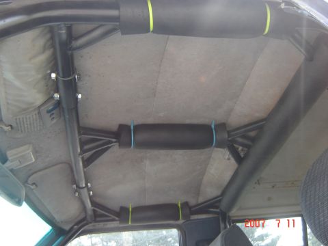 1993 Ford Bronco - The interior of a vehicle shows a custom roll cage with padded grab handles attached.