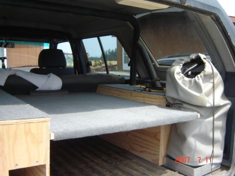 1993 Ford Bronco - Custom sleeping platform and storage built into the rear interior of an SUV.