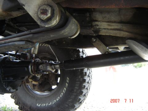 1993 Ford Bronco - Close-up of the undercarriage shows the suspension components and drive shaft of an off-road vehicle.