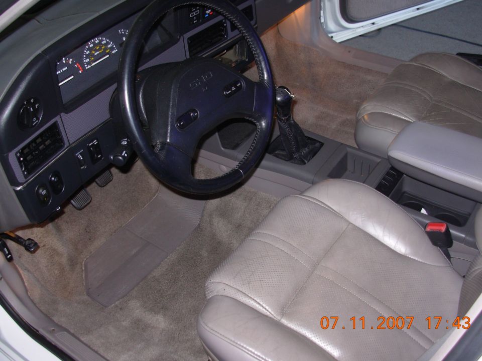 Interior of a 1995 Ford Taurus showing the dashboard, steering wheel, driver's seat, and center console