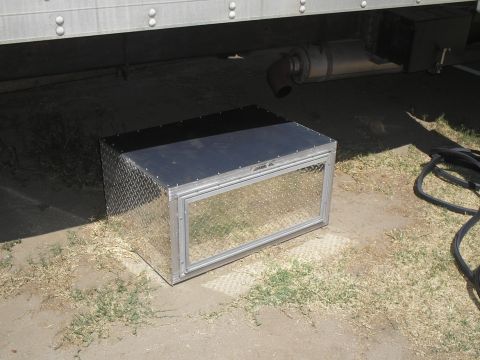 1999 Ford F-800 - An aluminum storage box with a clear window sits on the ground near the exhaust system of a large truck.