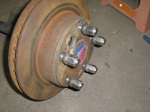 1990 Ford Bronco - Close-up of a corroded wheel hub assembly, showing the brake rotor and lug nuts.
