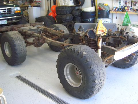 1996 Ford Bronco - The chassis and suspension of a vehicle are visible, equipped with oversized tires and modified for off-road use.