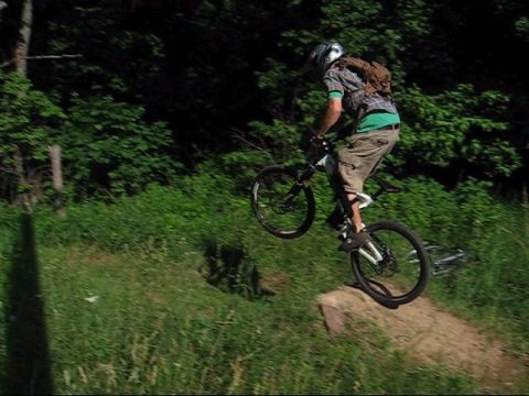 1997 Ford Probe - A mountain biker performs a jump on a dirt trail surrounded by trees and grass.