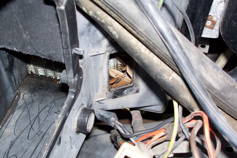 1984 Ford F-250 HVAC vent filled with leaves and debris, with visible wiring