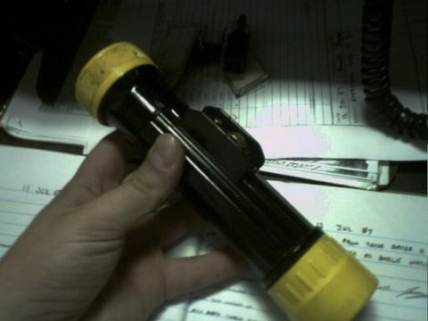 2001 Ford Crown Victoria - A black flashlight with yellow accents is held over papers that appear to be dated July 1987.