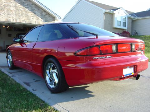 1997 Ford Probe - The rear of a red 1997 Ford Probe 24V is visible, parked in front of a residential garage.
