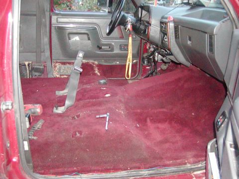 1991 Ford Bronco - The interior of a 1991 Ford Bronco shows a red carpeted floor with the seats removed and tools scattered around.