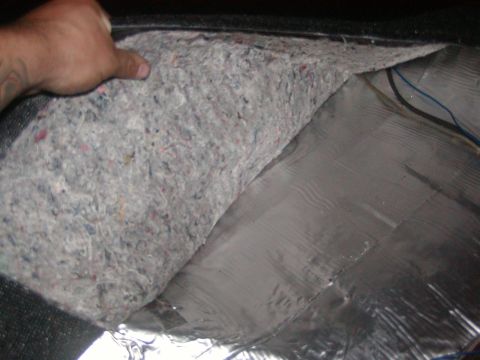 1991 Ford Bronco - Carpet padding is lifted to show the insulation and wiring beneath the floor of a vehicle.