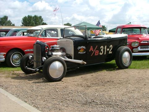 2001 Ford Fiesta - A classic hot rod is displayed outdoors with other vintage vehicles under a cloudy sky.