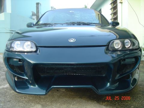 1995 Mazda MX-6 - Front view of a dark green coupe with an aggressive aftermarket body kit and custom headlights.