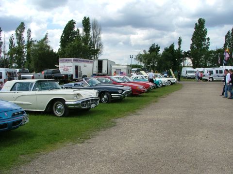 2001 Ford Fiesta - A collection of classic automobiles are displayed outdoors on a cloudy day, with spectators milling about.