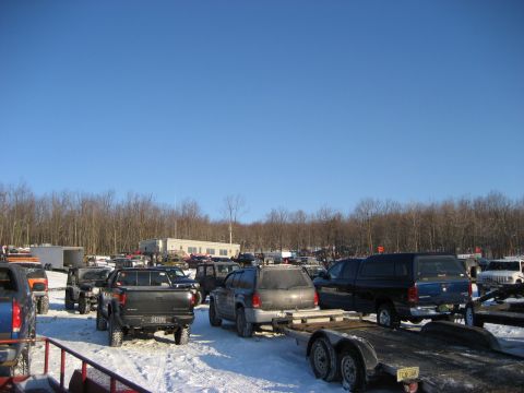 1991 Ford Bronco - A variety of trucks and SUVs are parked in a snowy lot under a clear blue sky.