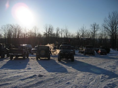 1991 Ford Bronco - Several trucks and SUVs are parked in a snowy area, with one vehicle emitting steam.