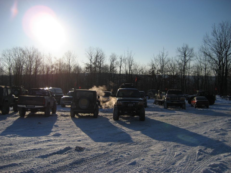 Trucks and SUVs parked in snow, one with steam rising from exhaust. The lead truck has a prominent grille