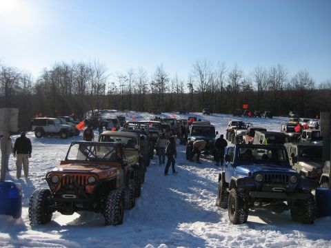 1991 Ford Bronco - A gathering of off-road vehicles in a snowy landscape under a bright blue sky.