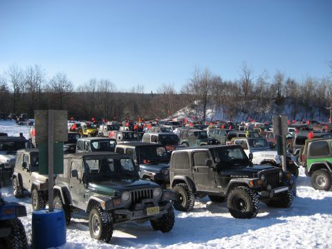 1991 Ford Bronco - A large gathering of Jeep Wranglers are parked in a snow-covered lot, indicating an off-road event or gathering.