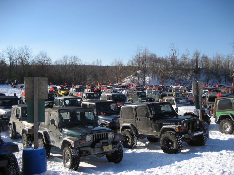 Several Jeep Wranglers parked in a snowy lot under a clear blue sky