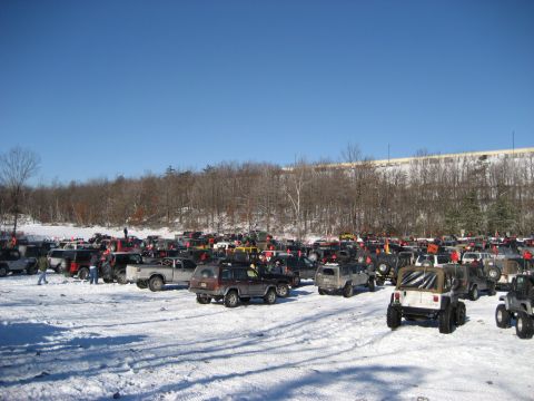 1991 Ford Bronco - A large gathering of off-road vehicles in a snow-covered field on a sunny day.