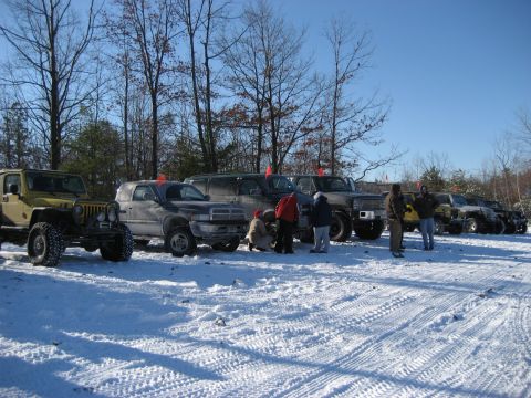 1991 Ford Bronco - A group of off-road vehicles are lined up in a snowy landscape under a clear blue sky.