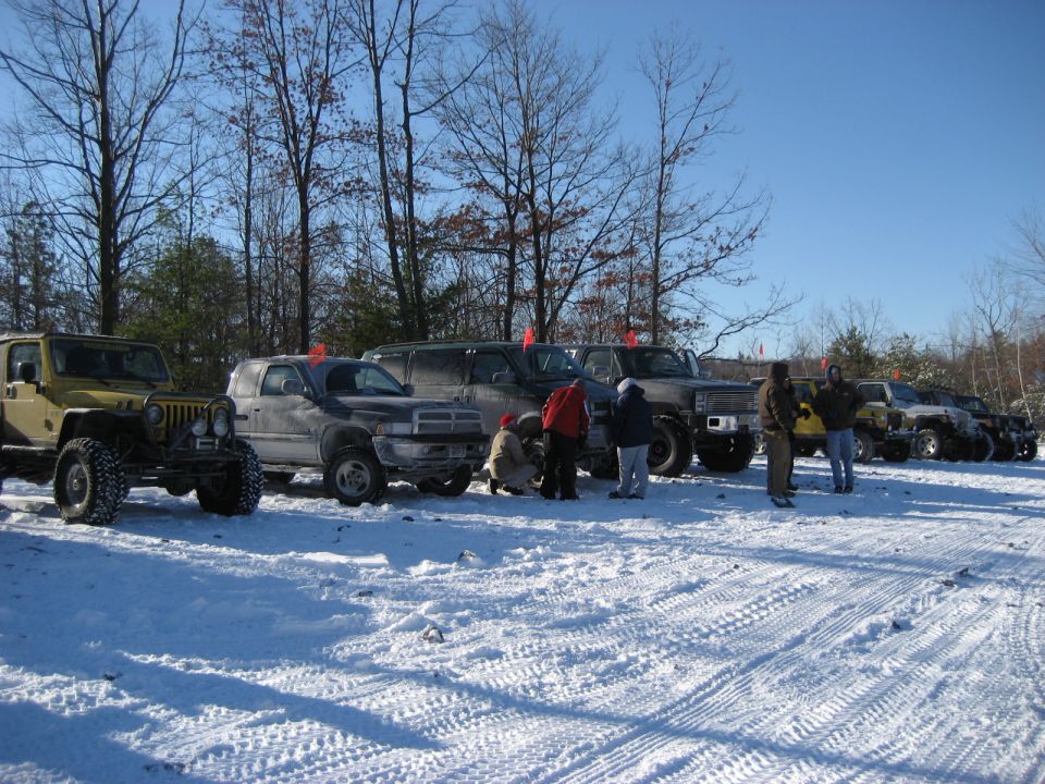 Several off-road vehicles parked in the snow on a sunny day