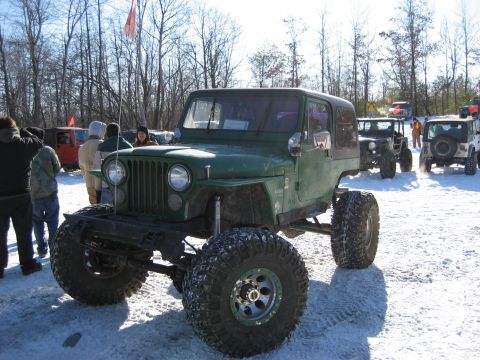 1991 Ford Bronco - Several off-road vehicles are parked in a snowy area with trees in the background.