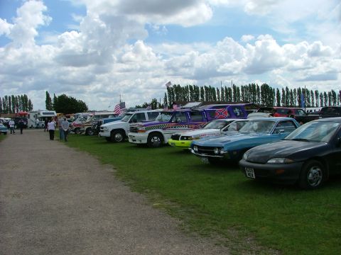 2001 Ford Fiesta - A variety of vehicles are lined up on a sunny day with a backdrop of trees and clouds.