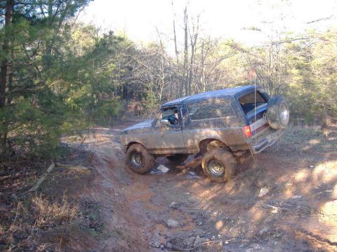 1991 Ford Bronco - Muddy 1991 Ford Bronco navigating a challenging off-road trail.