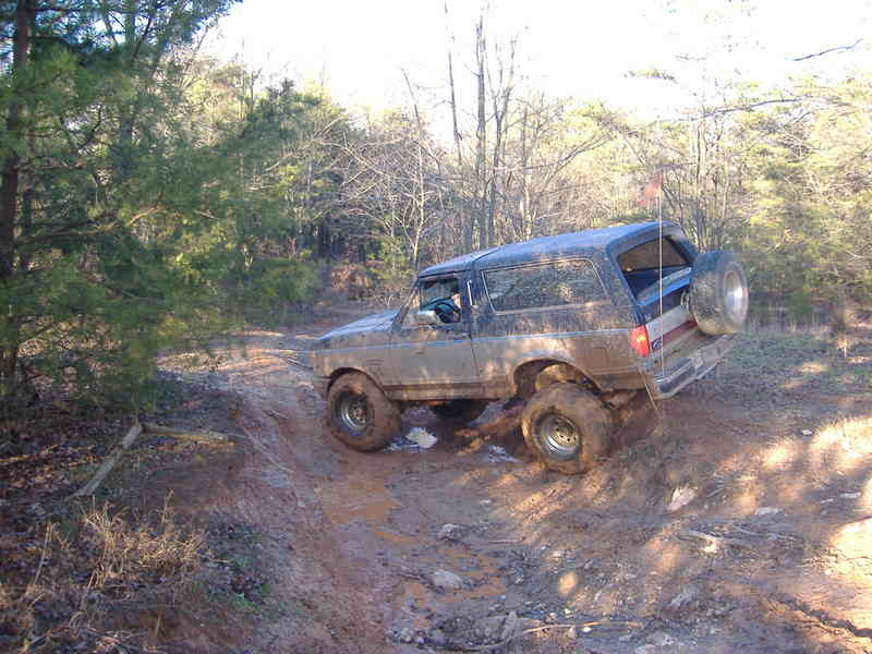 1991 Ford Bronco climbing a muddy hill off-road