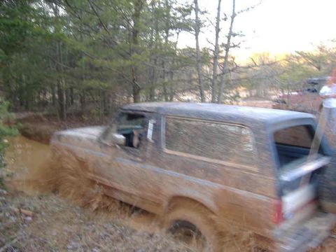 1991 Ford Bronco - Muddy 1991 Ford Bronco navigating a water-filled ditch off-road.