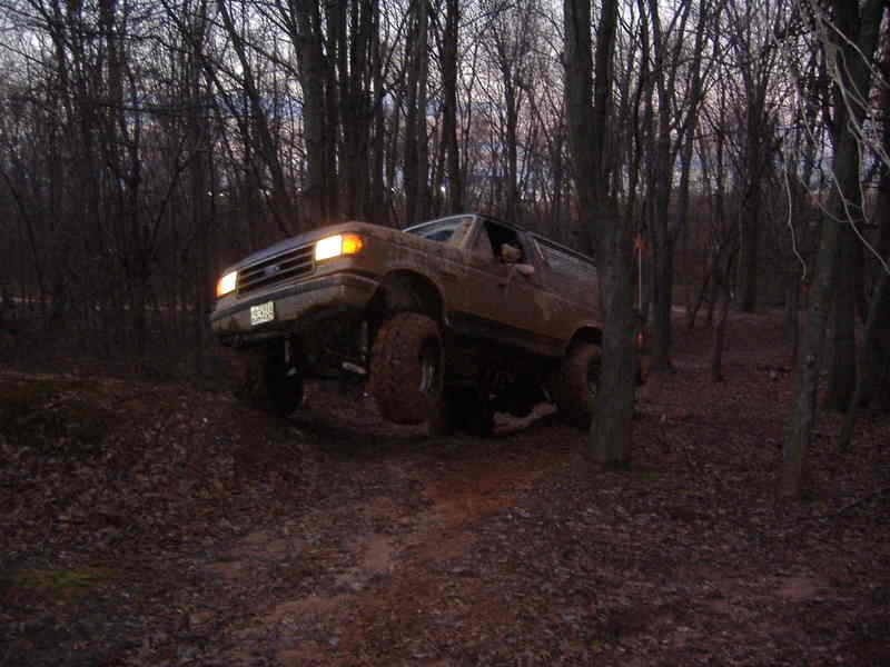 1991 Ford Bronco driving on a dirt path in a wooded area