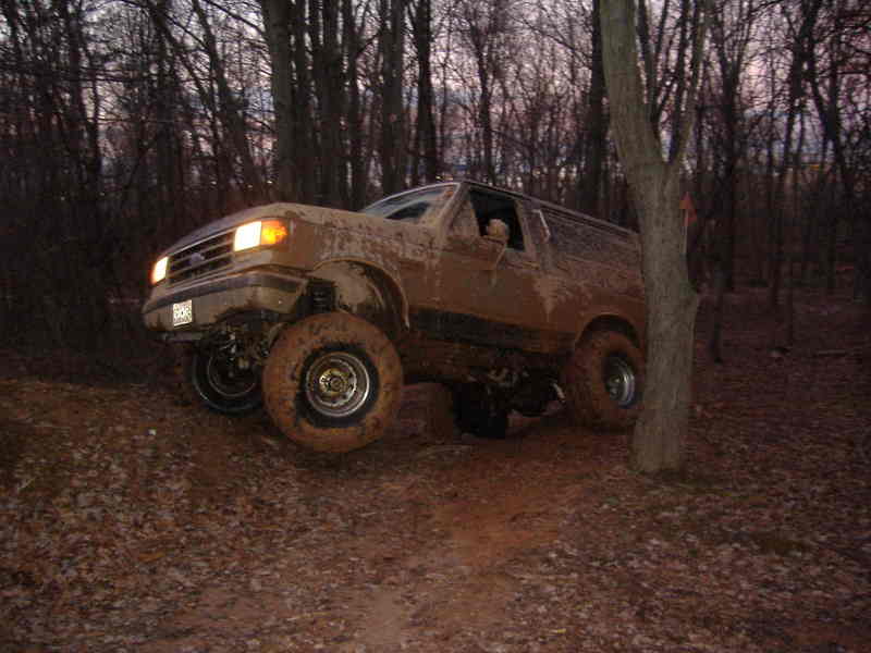 Muddy SUV driving on a dirt path in the woods