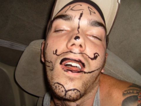 1992 Ford Bronco - A man with marker drawings on his face appears to be asleep or passed out inside a vehicle.