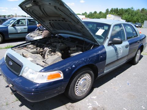1991 Ford LTD Crown Victoria - A two-tone Ford Crown Victoria, likely a former police vehicle, sits with its hood open, revealing the engine compartment.