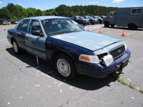 1991 Ford LTD Crown Victoria - A two-tone Ford Crown Victoria sits in a lot with other vehicles and traffic cones.