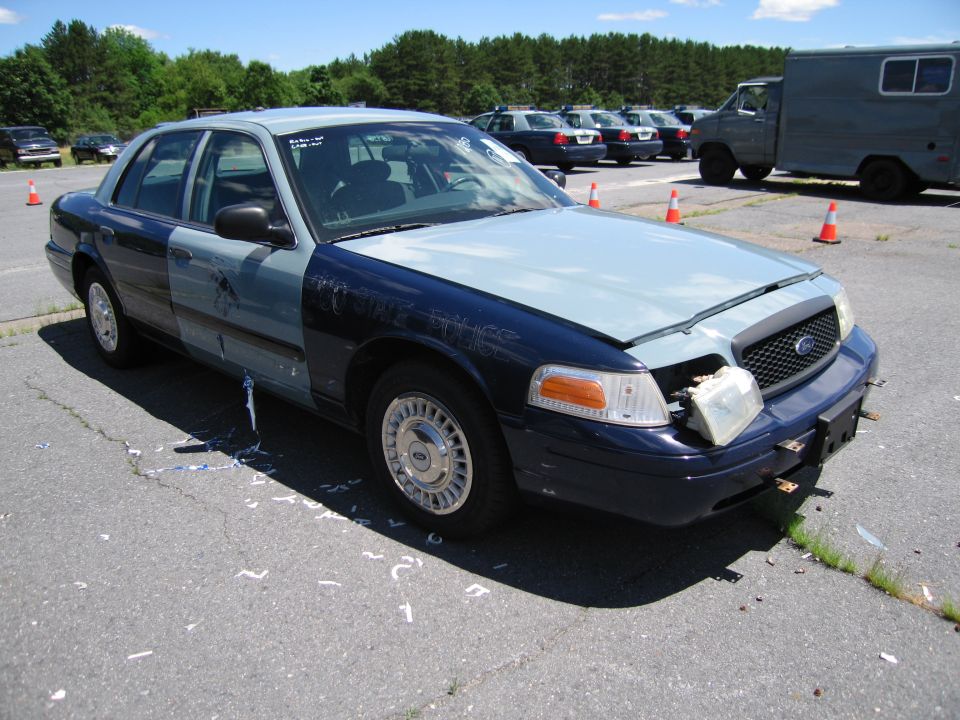 Dark blue and light blue Ford Crown Victoria with damaged headlight and hood ajar