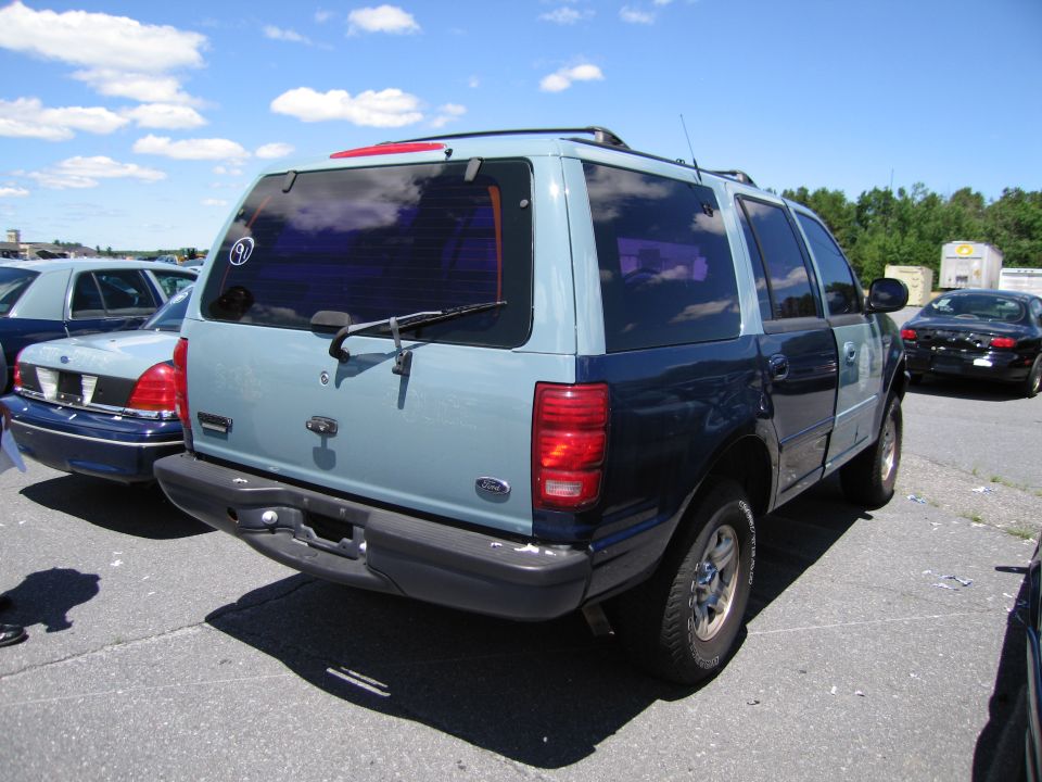 Two-tone Ford Expedition, rear view. Another car is parked to the left