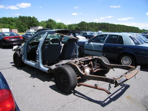 1991 Ford LTD Crown Victoria - A stripped-down 1991 Ford Crown Victoria LTD frame with interior visible, parked in a lot with other vehicles.