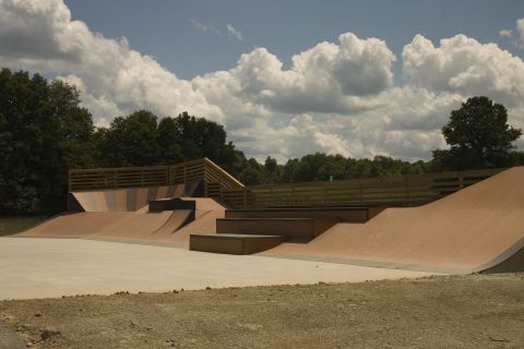 1997 Ford Probe - Outdoor skate park various ramps and wooden railings under a cloudy sky.