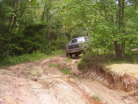 1991 Ford Bronco - Ford Bronco tackles an off-road trail with steep banks and loose dirt.
