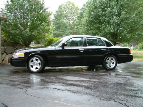 2002 Ford Crown Victoria - Side view of a black 2002 Ford Crown Victoria LX Sport sedan on a wet surface.