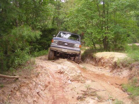 1991 Ford Bronco - This Ford Bronco is navigating a challenging off-road trail with steep inclines and sandy terrain.