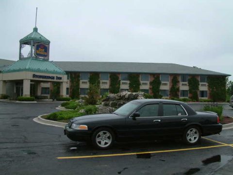 2002 Ford Crown Victoria - A black 2002 Ford Crown Victoria is parked in front of a hotel on a cloudy day.