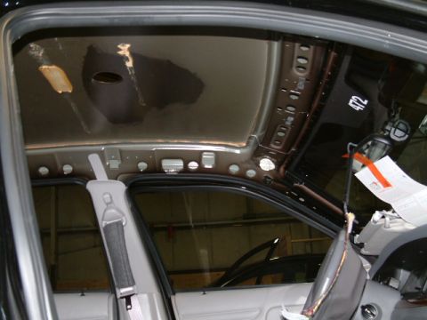2002 Ford Crown Victoria - The interior of a vehicle shows damage to the headliner and exposed metal framing, with some papers attached to the pillar.