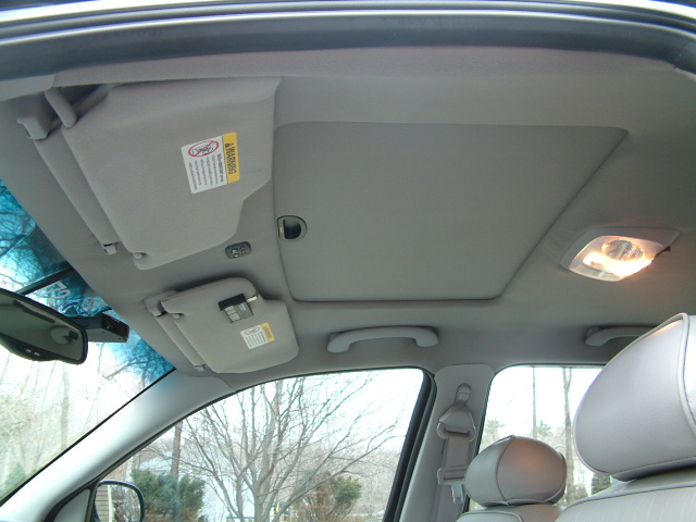 Gray car interior headliner with sun visors, dome light, and leather seats