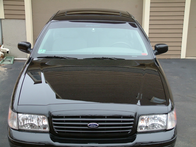 Front view of a black Ford sedan parked by a garage door