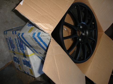 1993 Ford Taurus - A black alloy wheel is partially visible in an open cardboard box, next to boxes of KONI suspension parts.